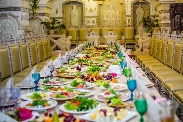 Schön servierter Tisch für Bankett im Restaurant. weiße Servietten und blaue und grüne Weingläser auf dem Tisch. Eine Reihe alter Stühle im Weihnachtscafé — Stockfoto