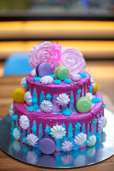 Colourful Fresh Macaroons on Beautiful cake for child s birthday. Candle in form of number 5 on cake. Blue with pink two-story cake for holiday. Happy birthday bright cake concept