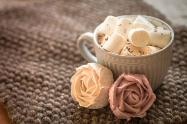 cup of cocoa or hot chocolate next to rose-shaped marshmallow. Warm cozy square background. Present for woman on valentines day. Sweets from natural products without GMOs.