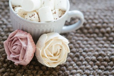 cup of cocoa or chocolate next to rose-shaped marshmallow. Warm cozy square background. Homemade pink marshmallow. Present for woman on valentines day. Sweets from natural products without GMOs.