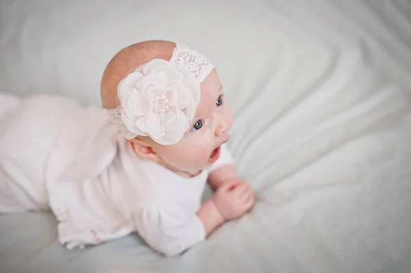 Yeni doğmuş bebek esniyor. Kız karyolada yüzüstü yatar ve ağzını açar..