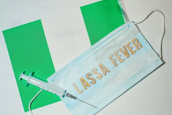 Nigerian flag under words Lassa fever outbreak concept. protective breathing mask and syringe. Lassa hemorrhagic fever LHF endemic in West Africa including Sierra Leone, Liberia, Guinea and Nigeria.