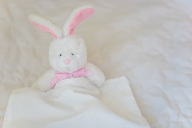 Oyuncak tavşan beyaz yatakta. Çocukların rol yapma oyunlarında yumuşak oyuncaklar.