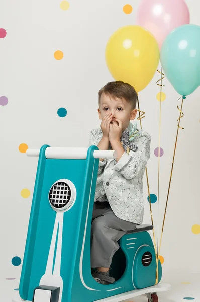 Menino em uma motocicleta de brinquedo em um fundo branco — Fotografia de Stock