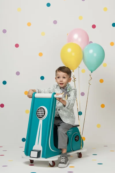 Menino em uma motocicleta de brinquedo em um fundo branco — Fotografia de Stock