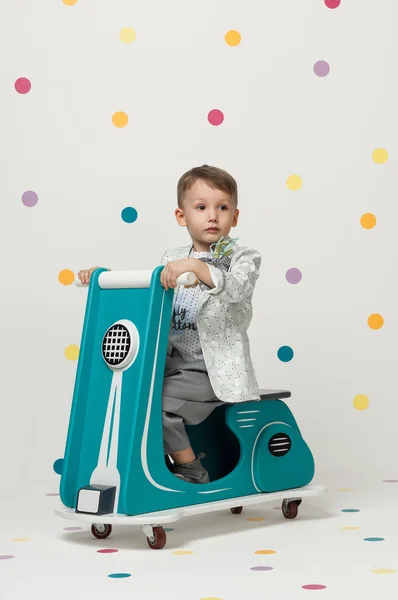 Menino em uma motocicleta de brinquedo em um fundo branco — Fotografia de Stock