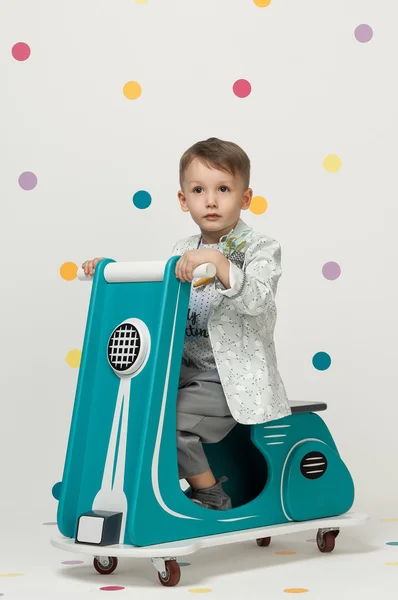 Menino em uma motocicleta de brinquedo em um fundo branco — Fotografia de Stock