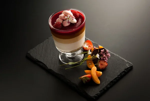 Один коктейль в стакане с кусочками фруктов на декоративном камне на темном фоне — стоковое фото