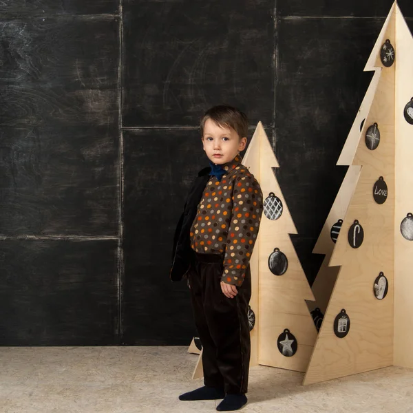 O menino ao lado de árvores de Natal decorativas — Fotografia de Stock