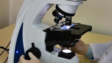Mikroskopla çalışan kadın laboratuvar asistanı. yakın çekim. Yavaş yavaş ve düzensiz hareketli kamera