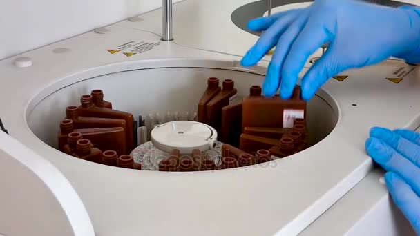 在医学实验室的女孩把血清样本放进机器进行分析 全自动生化分析 相机是固定的 — 图库视频影像