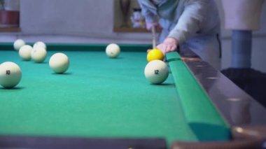 Beyaz toplu yeşil bilardo masası. Bilardo oynayan genç bir adam. Başarısız bilardo oyunu