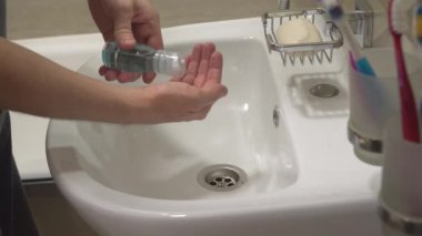Banyoda bir adam ellerini antiseptik antibakteriyel bir maddeyle yıkıyor. Coronavirus COVID-19 'a karşı koruma kavramı