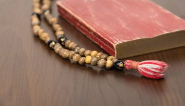 Müslüman dua boncukları ve ahşap bir arka planda izole edilmiş Kur 'an. İslam ve Müslüman kavramları