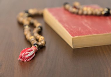 Müslüman dua boncukları ve ahşap bir arka planda izole edilmiş Kur 'an. İslam ve Müslüman kavramları