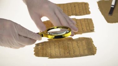 Bir araştırmacı, Kuran 'dan Arapça yazıları büyüteç ve ışıklı bir masa kullanarak öğrenir. Paleografi, antik Arapça yazılar üzerine çalışma.