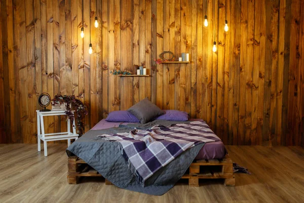 Room loft interior with bed, light bulbs and candles on dark wooden background