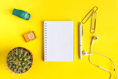 Defter üzerinde Ofis Masası ile bir dizüstü bilgisayar, kırtasiye ve ofis malzemeleri. Üstten Görünüm Danışma, düz sarı renk arka plan kavramı yatıyordu.