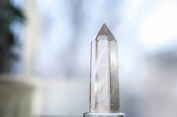 Saf şeffaf kuvarstan oluşan beyaz bir kristal. Bulanık arkaplanda Chalcedony mücevheri