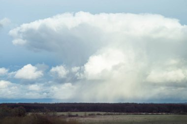 Bulutlu bir gökyüzünün altındaki bahar çayır vadisine bakın. Uzak yerlerin manzarası vahşi doğa. Büyük bulut