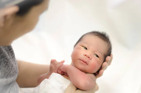Азиатская мать держит в руках голову своего новорожденного сына — стоковое фото
