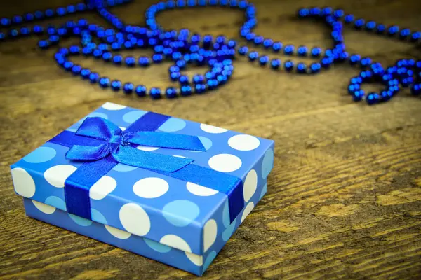 Gyönyörű kék ajándékot a fa háttér kék gyöngyökkel — Stock Fotó