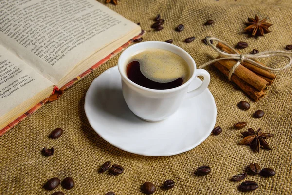 Cup of coffee on the background of burlap with a book. coffee beans . anise — Stock Photo, Image