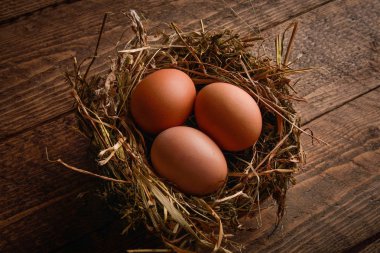 Ahşap arka plan üzerinde bir hasır saman içinde tavuk yumurta yuva