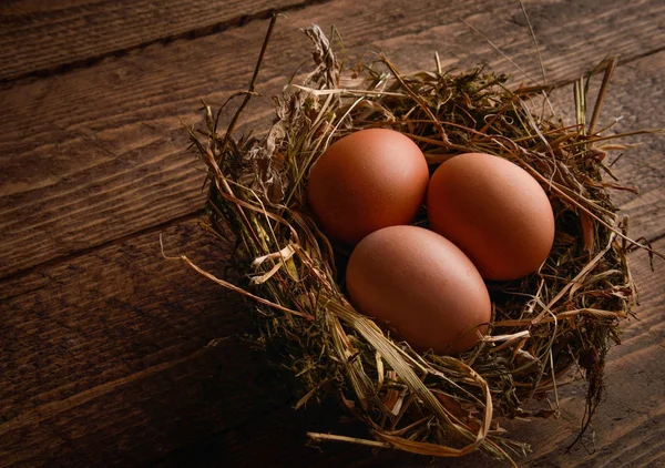 Ahşap arka plan üzerinde bir hasır saman içinde tavuk yumurta yuva