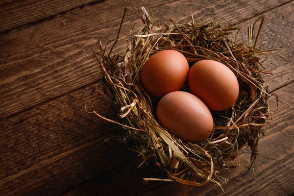Ahşap arka plan üzerinde bir hasır saman içinde tavuk yumurta yuva
