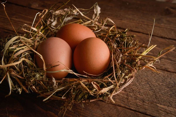 Ahşap arka plan üzerinde bir hasır saman içinde tavuk yumurta yuva