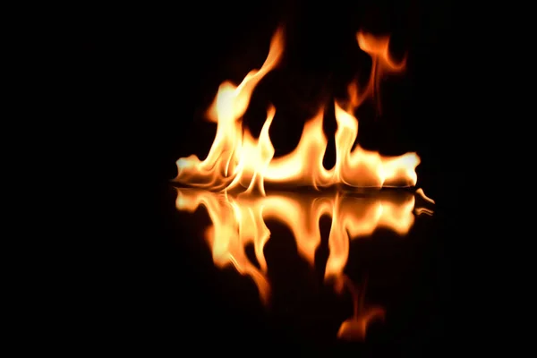 Пламя на черном фоне с зеркальным отражением — стоковое фото