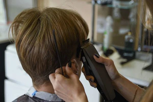 Servicios de peluquería. Un hombre le corta el pelo a un peluquero estilista en una peluquería. tijeras peine, clipper close-up.Peluquero en el trabajo. Cierre corte de cabello . —  Fotos de Stock