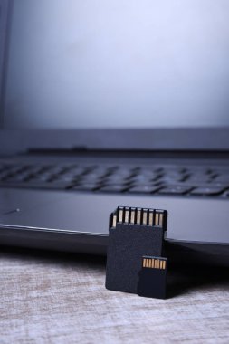 Tahta masadaki dizüstü bilgisayarda mikro SD hafıza kartı adaptörü. Kapat.