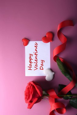 Sevgililer Günü arkaplanındaki tebrik kartı aşk sembolleri, pembe arka planda gözlüklü kırmızı kalp gülleri hediyeleri. Kopyalama alanı ve metin içeren üst görünüm. Düz konum