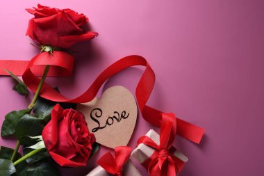 Sevgililer Günü arkaplanındaki tebrik kartı aşk sembolleri, pembe arka planda gözlüklü kırmızı kalp gülleri hediyeleri. Kopyalama alanı ve metin içeren üst görünüm. Düz konum