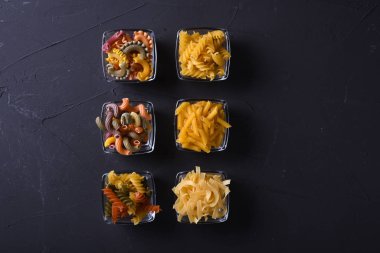 Makarna çeşitleri. Yemek pişirme konsepti. Koyu beton arkaplan wuth kopyalama alanı üzerindeki üst görünüm.