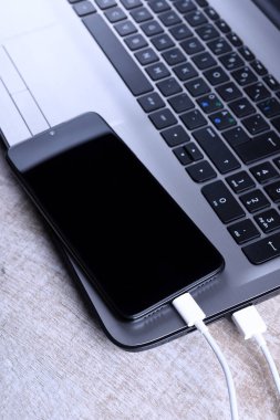 Usb kablosu, kablolu şarj aleti, şarj, şarj edilmiş ve veri transferi cep telefonu, ahşap zemin üzerinde dizüstü bilgisayarı olan akıllı telefon, masa üstü görünümü