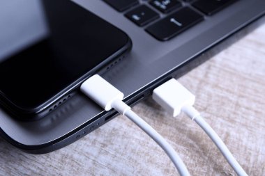 Usb kablosu, kablolu şarj aleti, şarj, şarj edilmiş ve veri transferi cep telefonu, ahşap zemin üzerinde dizüstü bilgisayarı olan akıllı telefon, masa üstü görünümü