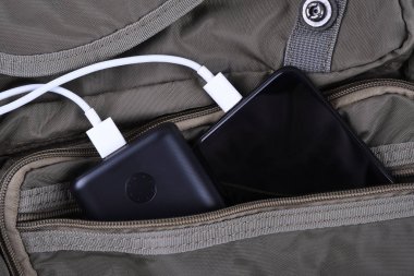 Telefon şarjı, elektrik faturası akıllı telefon, enerji bankasıyla cep telefonu. Sırt çantasındaki Güç Bankası alanının derinliği