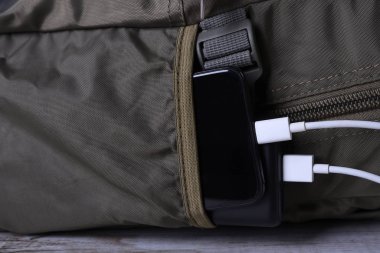 Telefon şarjı, elektrik faturası akıllı telefon, enerji bankasıyla cep telefonu. Sırt çantasındaki Güç Bankası alanının derinliği