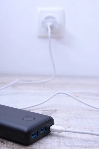 Чорний телефон, підключений до гнізда на стіні для зарядки на дерев'яному фоні — стокове фото
