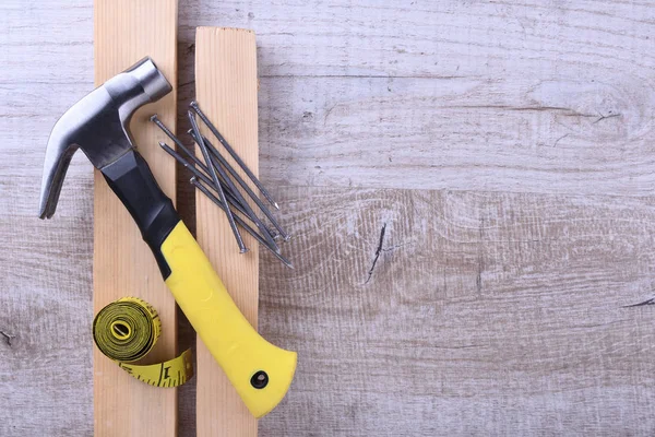 Ferro da stiro a martelli, nastro centimetri e chiodi su sfondo di legno — Foto Stock