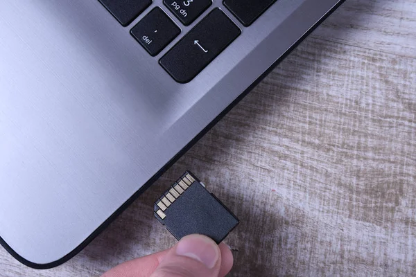 Adapter karty pamięci Micro Sd na szarej klawiaturze laptopa na drewnianym stole. zbliżenie — Zdjęcie stockowe