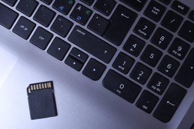 Tahta masadaki gri dizüstü bilgisayarda mikro Sd hafıza kartı adaptörü. Kapat.