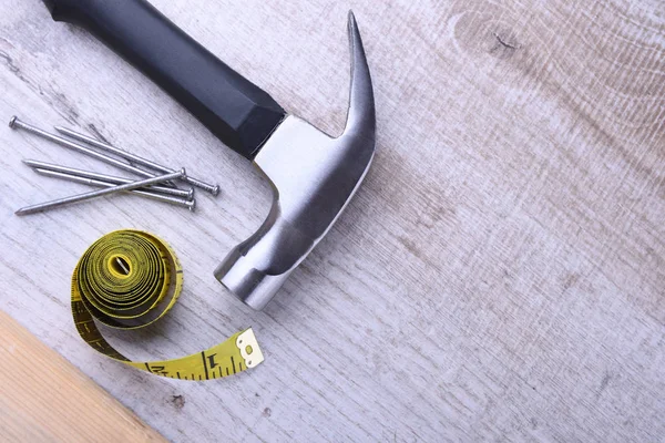 Ferro da stiro a martelli, nastro centimetri e chiodi su sfondo di legno — Foto Stock