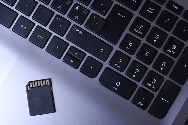 Adapter karty pamięci Micro Sd na szarej klawiaturze laptopa na drewnianym stole. zbliżenie — Zdjęcie stockowe