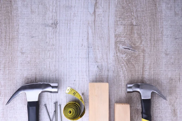 Ferro martelo, fita de centímetros e unhas em fundo de madeira — Fotografia de Stock