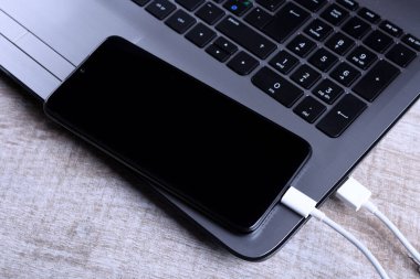 Usb kablosu, kablolu şarj aleti, şarj, şarj edilmiş ve veri transferi cep telefonu, ahşap zemin üzerinde dizüstü bilgisayarı olan akıllı telefon, masa üstü görünümü