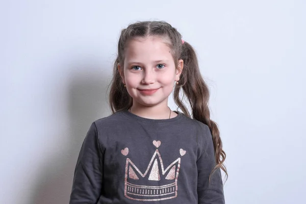 Porträt eines kleinen weißen Mädchens, das auf grauem Hintergrund lächelt — Stockfoto